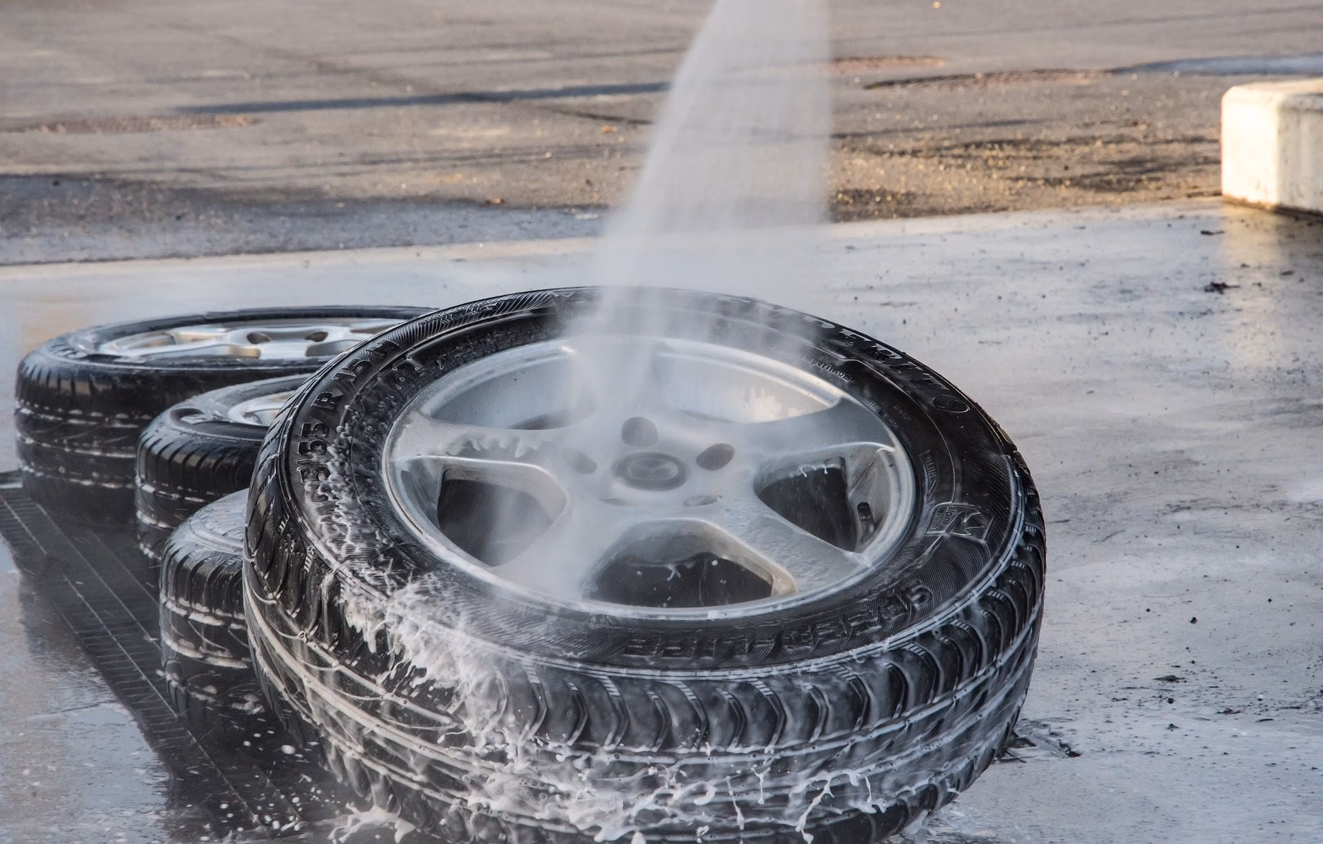 Person cleaning a car wheel and tire during a wash