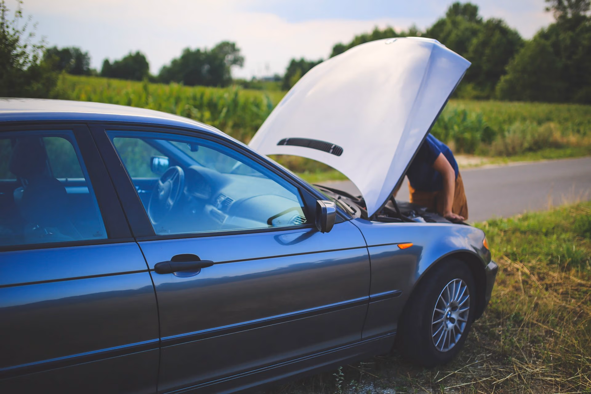 Car hood open with person checking battery—diagnosing why car won't start