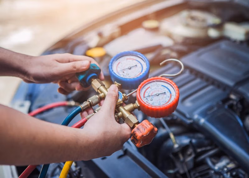 Mechanic checking a car air conditioning system with diagnostic monitor