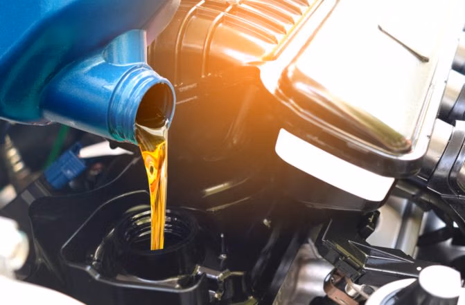 Person pouring motor oil into a car engine during an oil change