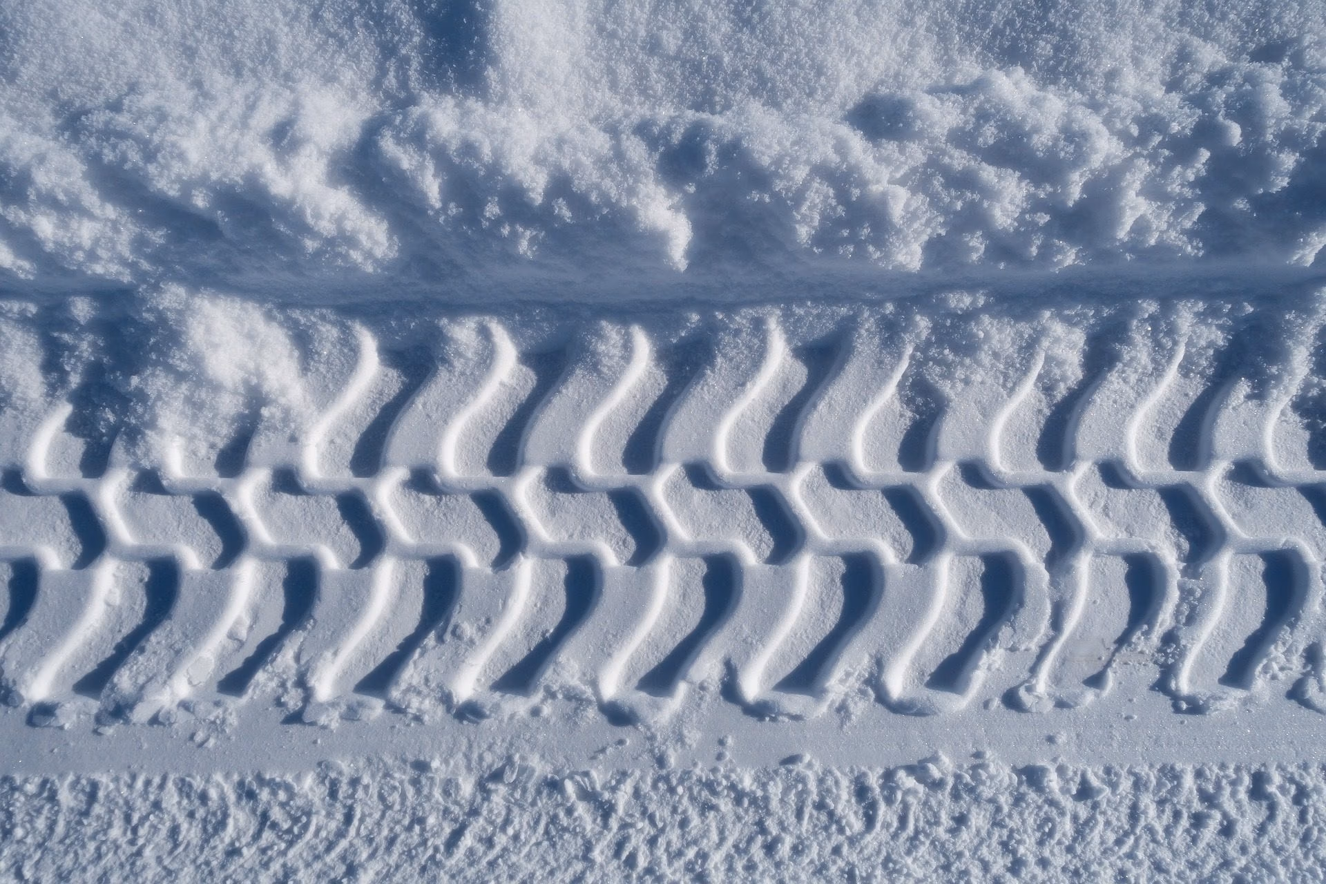 Tire tracks in snow near a parked vehicle in winter conditions